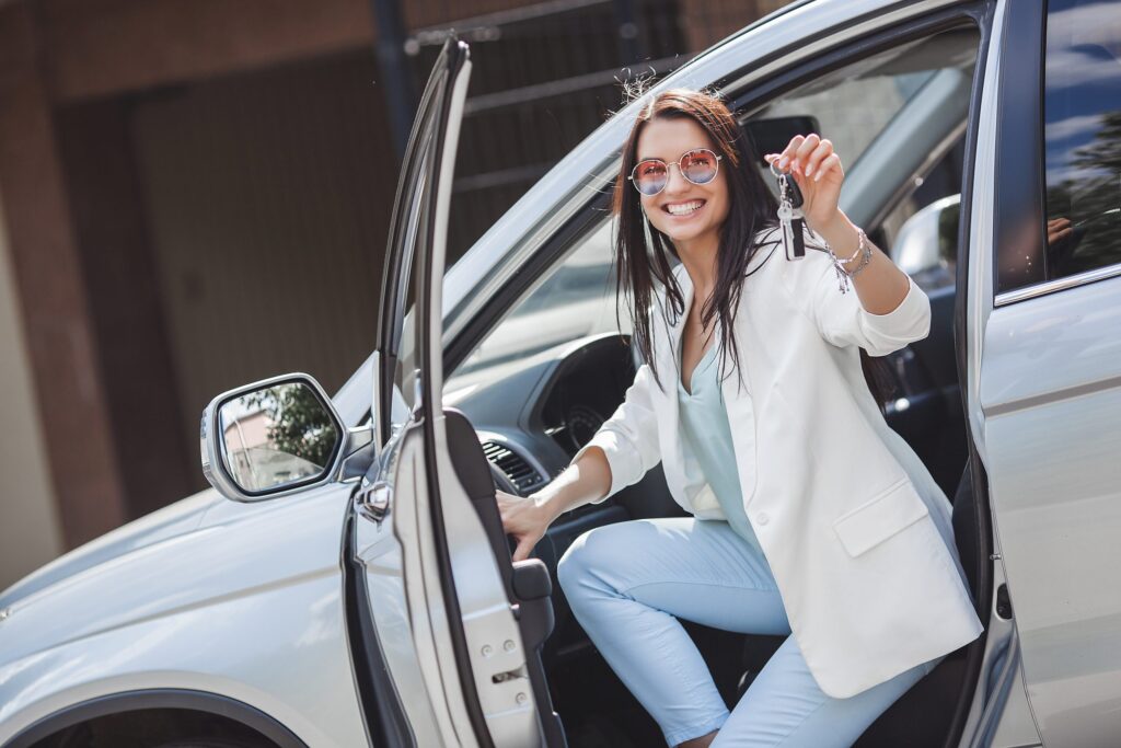 Young attractive woman just bought a new car. female holding keys from new automobile