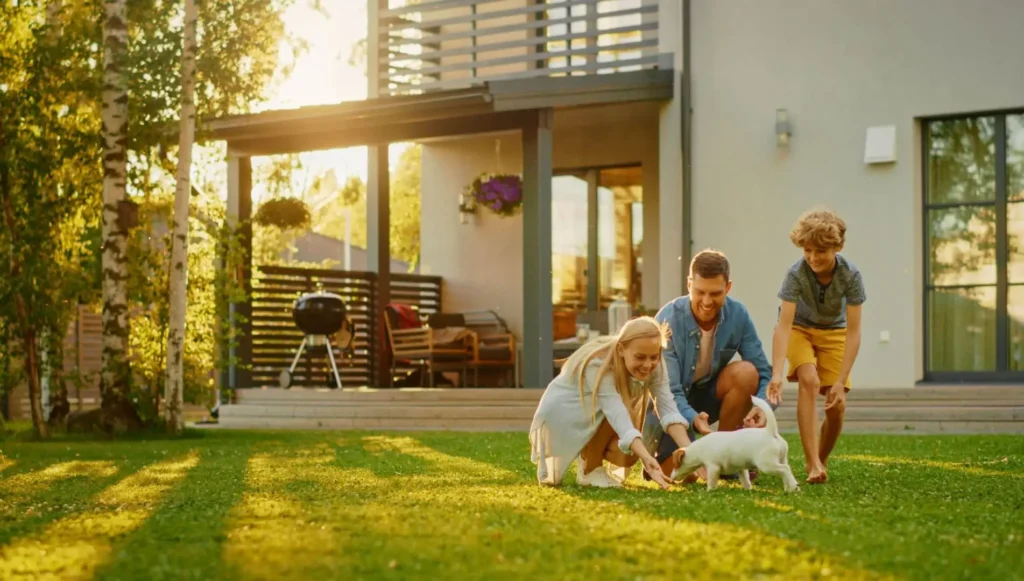 Picture of a young family playing with a puppy in their backyard of their home on a summer day